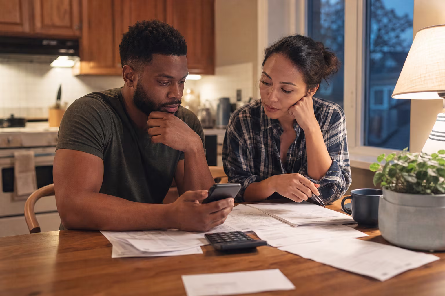 Two people working through costs at a kitchen table with papers and a calculator