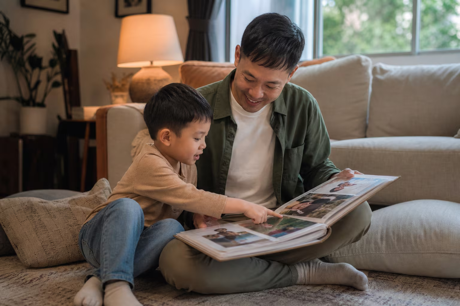 An adult and a child sitting on the floor looking at a photo album together