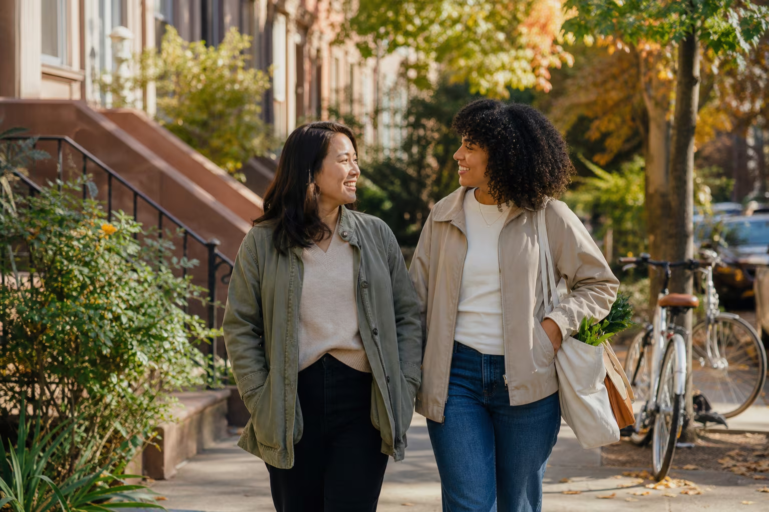 Two people walking together along a residential street on a bright day, in easy conversation