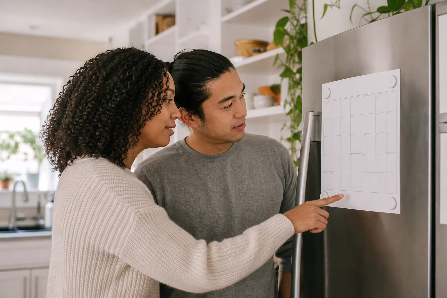 Two people looking together at a shared calendar on the fridge door